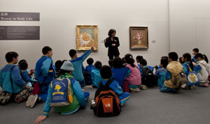 A boy raises his hand to answer a tour guide